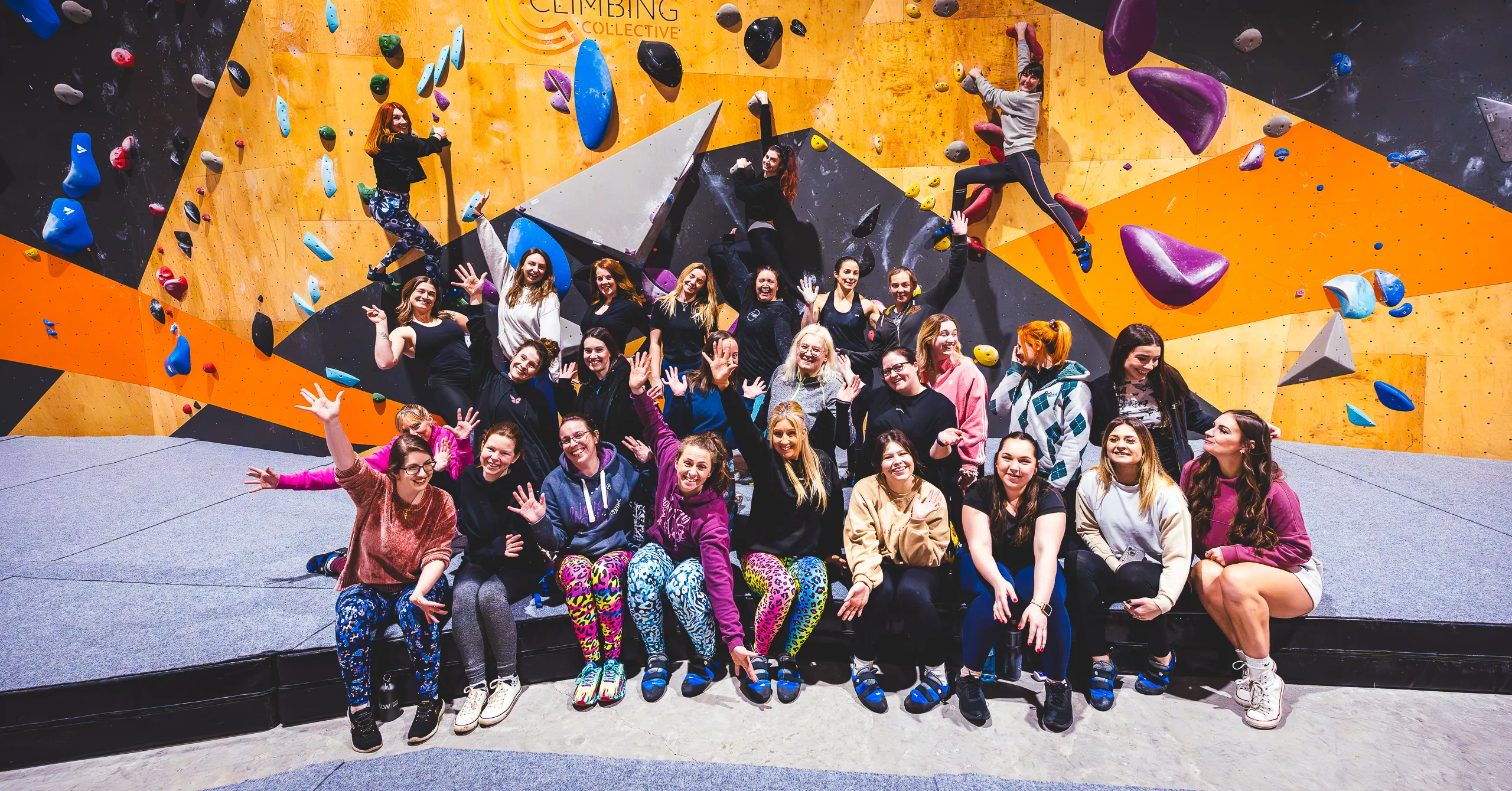 group of climbers pose with some people half way up the wall